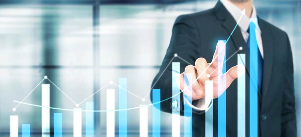 A person in a suit points at a digital screen displaying bar and line graphs, indicating digital marketing growth.